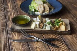 The hot salad with meat, and cheese plate on a wooden table. photo