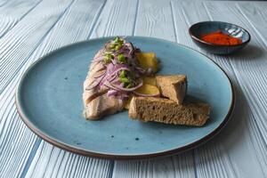 Fried potatoes and herring fish with onion on a wooden table. photo