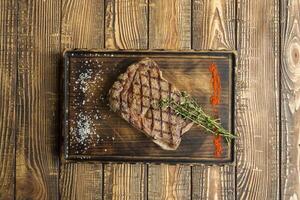 Grilled meat with sauce and rosemary on a wooden table. photo