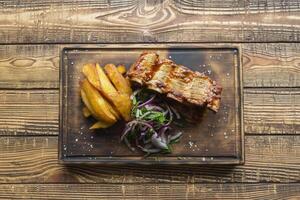 Fried potatoes with grilled meat on a wooden table. photo