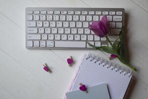 Computer keyboard and notebook with empty sheet. Modern workplace. photo