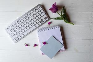 Computer keyboard and notebook with empty sheet. Modern workplace. photo