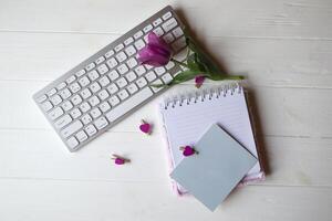 Computer keyboard and notebook with empty sheet. Modern workplace. photo