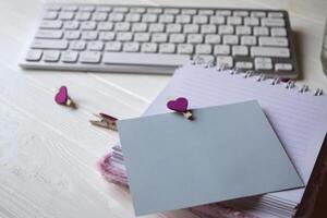 Computer keyboard and notebook with empty sheet. Modern workplace. photo