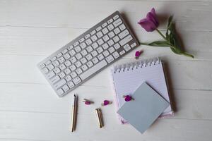 Computer keyboard and notebook with empty sheet. Modern workplace. photo