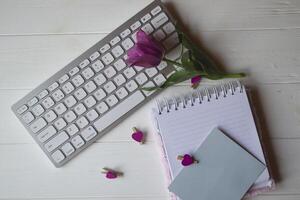 Computer keyboard and notebook with empty sheet. Modern workplace. photo