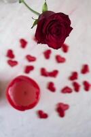 Red rose, hearts and candle on a table. photo