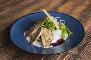 The hot salad with meat on a wooden background. photo