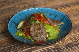 The salad with meat on the wooden table. photo