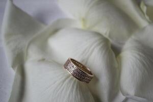 Wedding ring on white petals of roses. photo