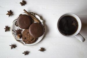 A cup of coffee with chocolate cookies, on a white wooden table. photo