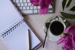 Beautiful workplace with coffee and peony. photo