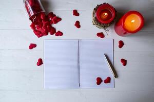 Red candles, love hearts and notebook on the table. Beautiful bckground with copy space. photo