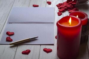 rojo velas, amor corazones y cuaderno en el mesa. hermosa fondo con Copiar espacio. foto