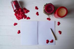 Red candles, love hearts and notebook on the table. Beautiful bckground with copy space. photo
