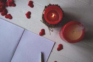 Red candles, love hearts and notebook on the table. Beautiful bckground with copy space. photo