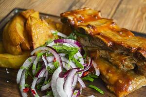 A grilled pork and fried potatoes on the wooden background. photo