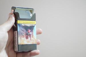 A hand holding a cigarette box photo