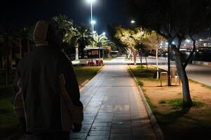 A man is walking down a sidewalk at night photo