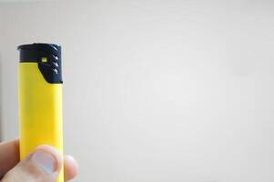 A person is holding a yellow lighter photo