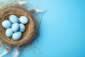 Easter holiday celebration banner greeting card with pastel painted eggs in bird nest on bright blue backround tabel texture. Top view, flat lay with copy space photo