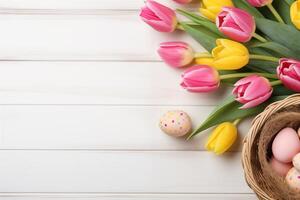 Easter holiday celebration banner greeting card banner with pink painted eggs in bird nest basket and yellow tulip flowers on white wooden background tabel texture. photo