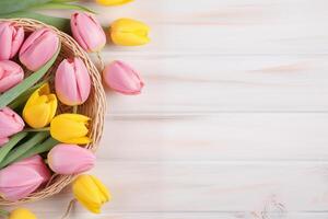 Easter holiday celebration banner greeting card banner with pink painted eggs in bird nest basket and yellow tulip flowers on white wooden background tabel texture. photo