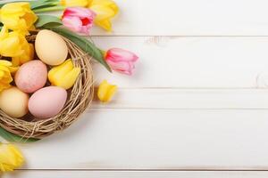 Easter holiday celebration banner greeting card banner with pink painted eggs in bird nest basket and yellow tulip flowers on white wooden background tabel texture. photo