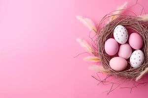 Easter holiday celebration banner greeting card with pastel painted eggs in bird nest on bright pink backround tabel texture.. Top view, flat lay with copy space photo