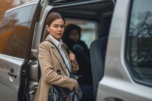 Female waits a business people to let them in a minivan taxi, keeping door open. Concept of business trips and transportation service photo