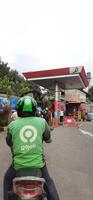 Queue of vehicles public refueling at Pertamina gas station or Pom Bensin during the day. Bekasi, West Java, Indonesia - April 4 2024 photo