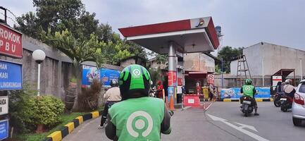 Queue of vehicles public refueling at Pertamina gas station or Pom Bensin during the day. Bekasi, West Java, Indonesia - April 4 2024 photo