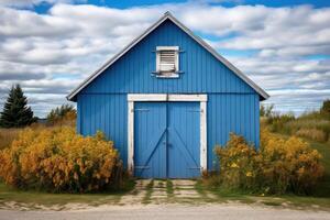 A classic blue barn with white trim located amidst a vast countryside landscape under a blue sky with clouds photo