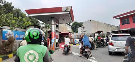 Queue of vehicles public refueling at Pertamina gas station or Pom Bensin during the day. Bekasi, West Java, Indonesia - April 4 2024 photo