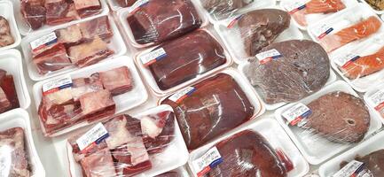 Fresh raw meat chicken and beef on display in supermarket cold shelves. Bekasi, West Java, Indonesia - March 8 2024 photo