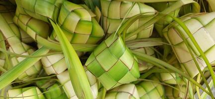 ketupat o arroz bola de masa hervida. un tradicional arroz caja hecho desde joven Coco hojas para Cocinando arroz vendido en tradicional mercado preparación para el eid al-fitr fiesta para musulmán foto