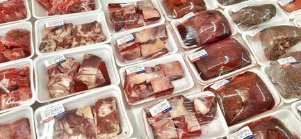 Fresh raw meat chicken and beef on display in supermarket cold shelves. Bekasi, West Java, Indonesia - March 8 2024 photo