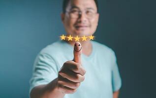 Man in good mood, smiling thinking positive hand thumb up with pop up five star and emotion smiley face icon for feedback review. Customer experience satisfaction Best Excellent Services Rating. photo