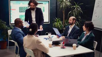 team leider sharing klemborden met de laatste prestatie statistieken naar bespreken over werk rendement en optimalisatie gedurende zakelijke briefing ontmoeting. manager is overleg plegen zijn personeel. camera b. video