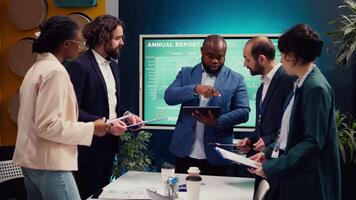 Supervisor and employees attend a status update meeting with their progress portfolios on the current business project. Team leader reviewing marketing strategies and budget planning. Camera B. video