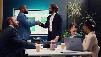 Business partners celebrate the beginning of a new project between their companies, shaking hands in a meeting. Leaders forging an agreement to develop the corporation and collect resources. Camera B. video