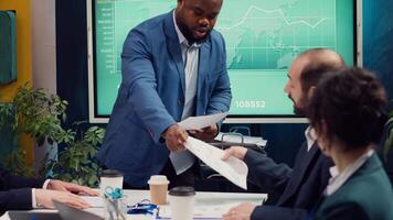 Project manager meeting with his executive team in a boardroom office, looking into updates on regulatory changes that can affect their tasks. Leader sharing gathered analysis on papers. Camera A. video