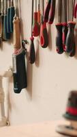 Vertical Close up of electric router with woodworking tools on rack in background in workshop. Focus on hand powered equipment in front of chisels, screwdrivers, on wall in carpentry studio, panning shot video