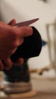 Vertical Carpenter putting sandpaper on piece of plastic, creating abrasive sponge to smooth surfaces. Man preparing necessary gear for furniture assembling job in studio, close up shot, camera A video