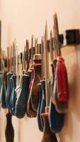 Vertical Chisels, screwdrivers, wrench and pliers on wall in furniture assembly shop used for carving wood surfaces. Close up of woodworking gear on rack in carpentry studio, panning shot video