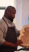 Vertical Portrait of jolly man grinning while inspecting wood in furniture assembling shop, satisfied by quality. Joyful woodworking expert in studio evaluates lumber block, pleased by lack of damage, camera B video