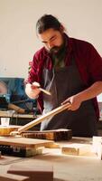 Vertical Cabinetmaker applying varnish on wooden surface to prevent damage and provide layer of protection. Woodworking expert in studio doing finishing on wood plank, putting coats of oil, camera B video