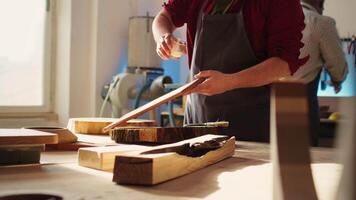 la lavorazione del legno specialista l'applicazione vernice su legna per costruire su protettivo strato. ebanista nel montaggio negozio laccatura di legno tavola dopo levigatura superficie per garantire levigatezza, vicino su sparo, telecamera B video