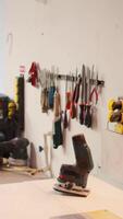 Vertical Chisels, screwdrivers, wrench and pliers on wall in furniture assembly shop next to electric router on workbench. Close up of woodworking gear on rack in joinery and power tool video