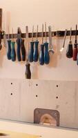 Vertical Chisels, screwdrivers, wrench and pliers on wall in carpentry studio, panning shot. Close up of various woodworking tools on rack in workshop used for repairing or creating wooden objects video